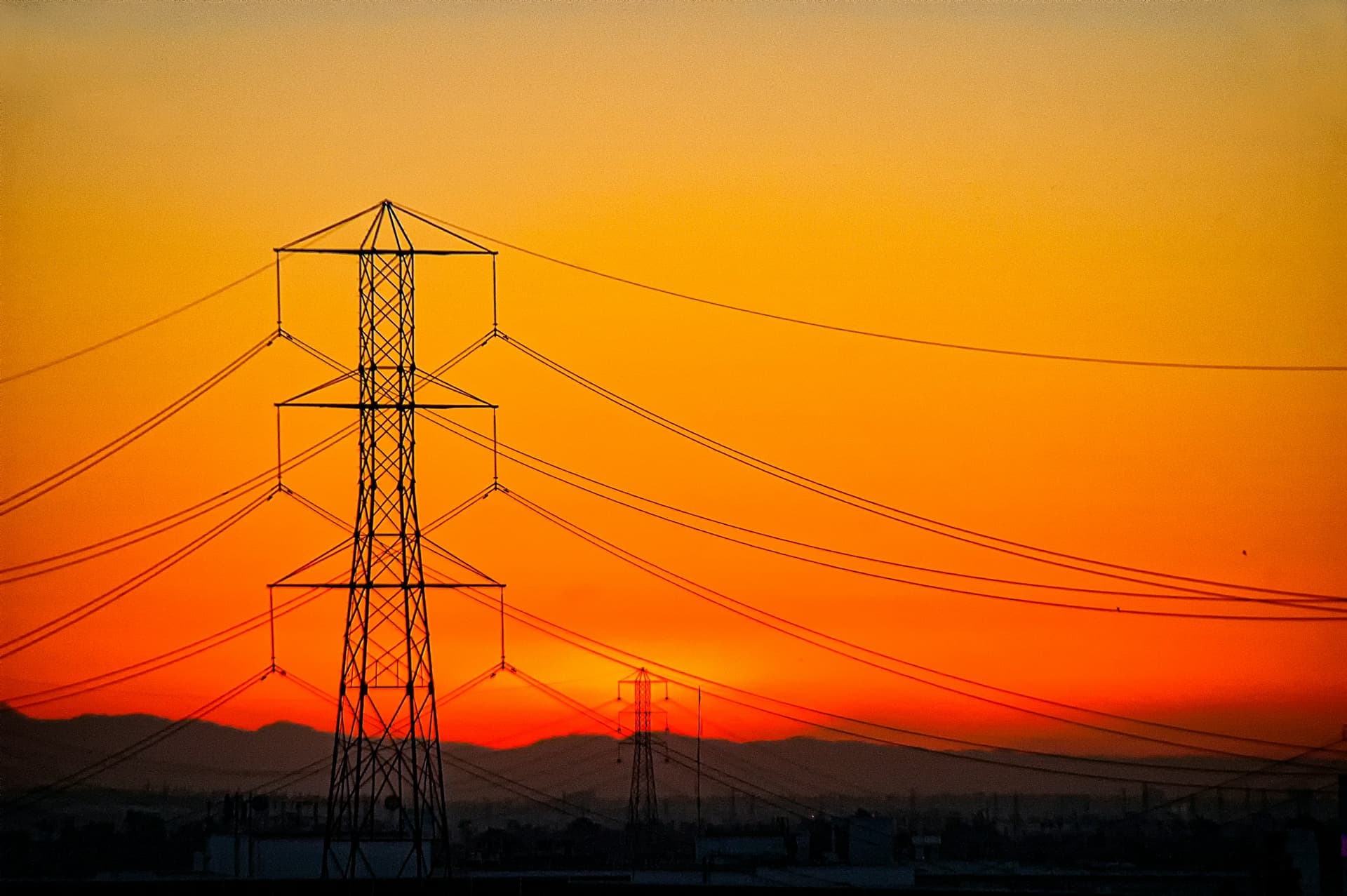 Transmission towers silhouetted against a golden sunset sky